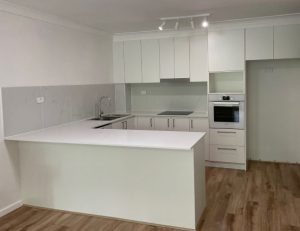 kitchen renovations sydney- a kitchen with a white island and a wood floor